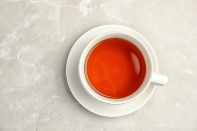 Photo of Porcelain cup of black tea on table, top view