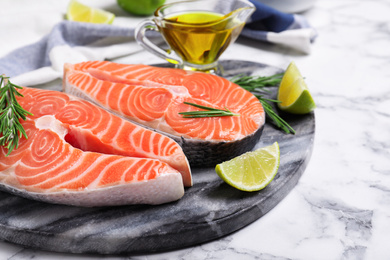 Photo of Fresh raw salmon with rosemary and lime on stone board. Fish delicacy