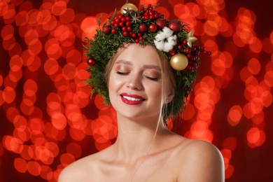 Beautiful young woman wearing Christmas wreath on blurred background. Bokeh effect