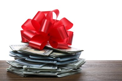 Photo of Pile of dollar bills with red bow on wooden table against white background. Space for text
