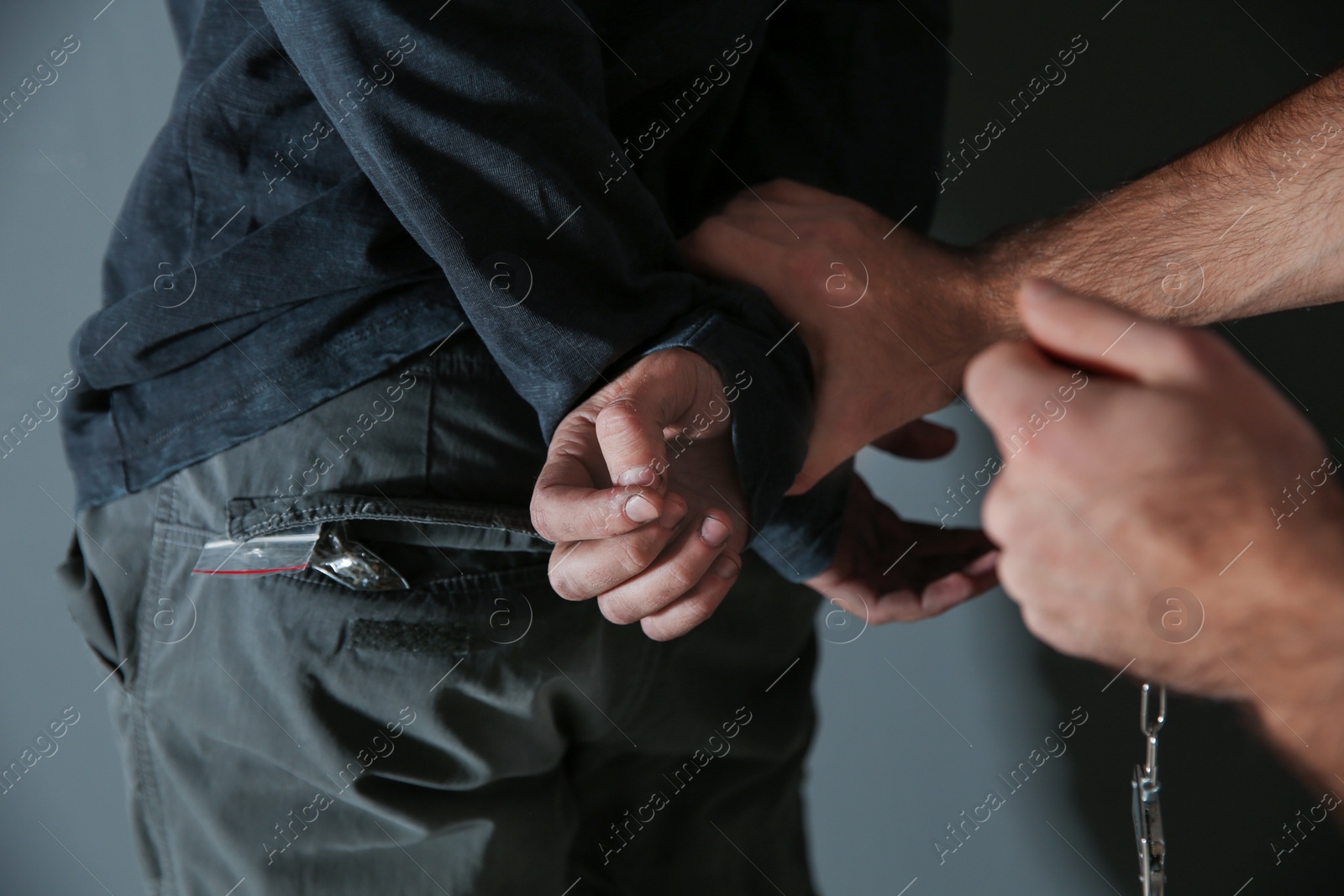 Photo of Man putting handcuffs on drug dealer, closeup view