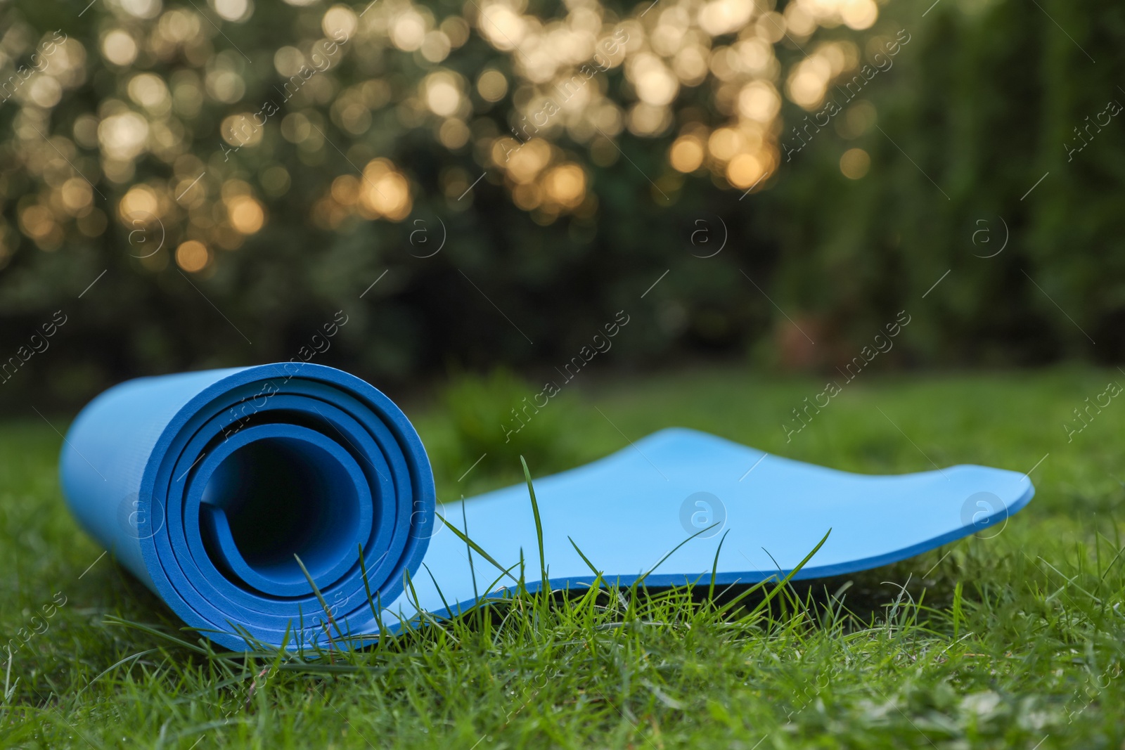 Photo of Blue karemat or fitness mat on green grass outdoors