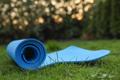 Blue karemat or fitness mat on green grass outdoors