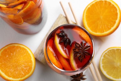Photo of Aromatic punch drink and ingredients on white table, flat lay