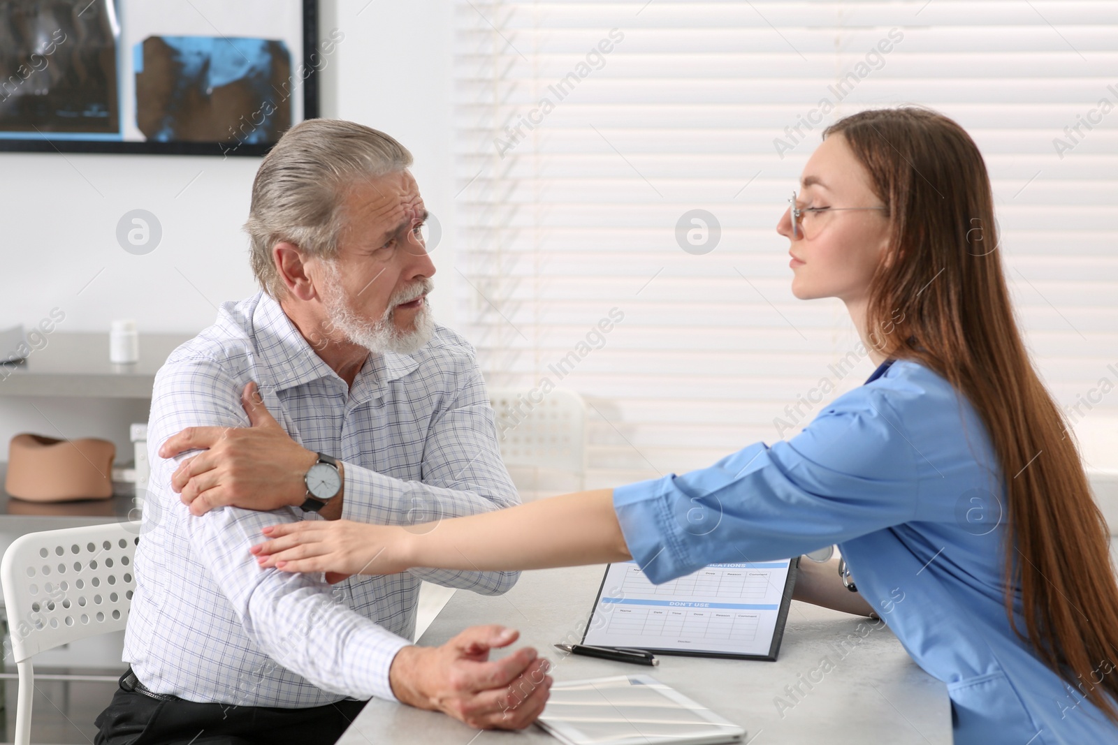 Photo of Orthopedist examining patient with injured arm in clinic