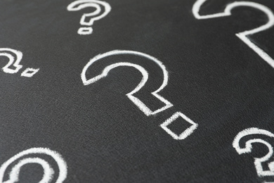 Question marks drawn with chalk on blackboard, closeup