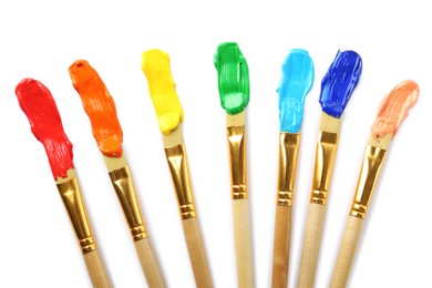 Photo of Brushes with colorful paints and strokes on white background, top view