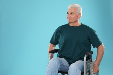 Senior man in wheelchair on color background. Space for text