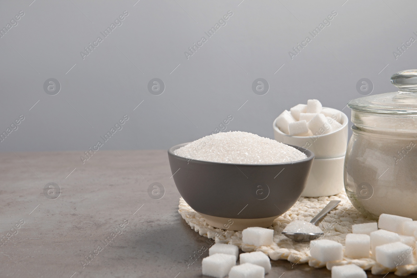 Photo of Different types of sugar on grey table, space for text