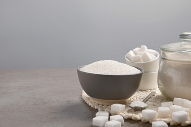 Different types of sugar on grey table, space for text