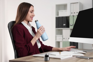 Photo of Woman holding light blue thermos bottle at workplace