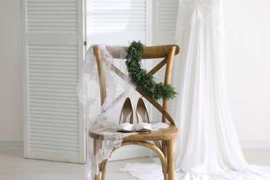 Photo of Pair of white high heel shoes, veil and wedding dress indoors