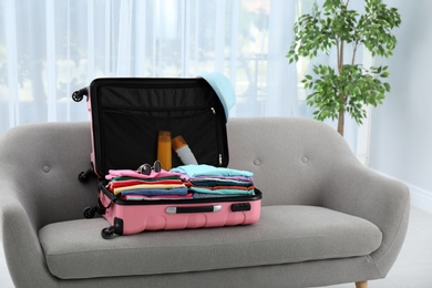 Modern suitcase packed for journey on sofa indoors