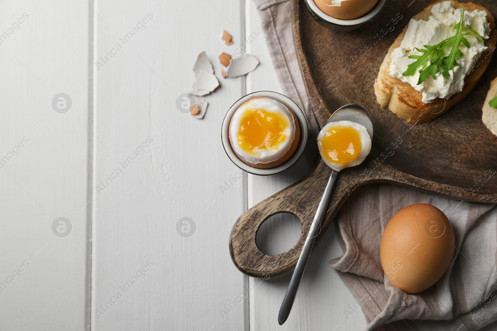 Photo of Breakfast with soft boiled egg served on white wooden table, flat lay. Space for text