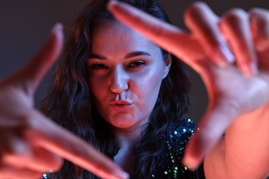 Portrait of beautiful young woman on color background with neon lights