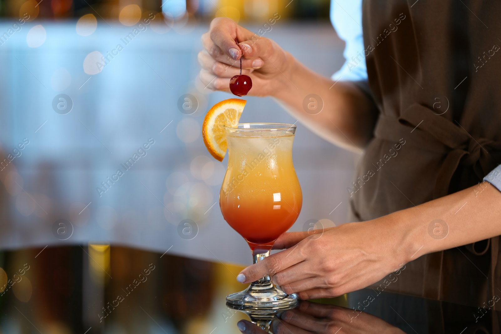 Photo of Bartender decorating glass of fresh alcoholic cocktail at bar counter