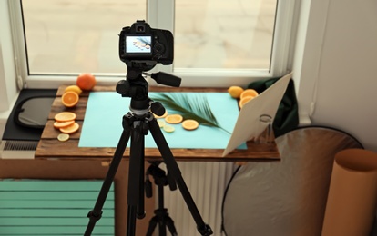Photo of Professional camera with picture of cut fruits and palm leaf on display in studio. Food photography