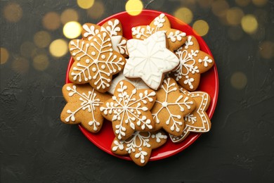 Tasty Christmas cookies with icing on black table, top view