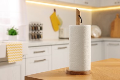 Roll of white paper towels on wooden table in kitchen, space for text