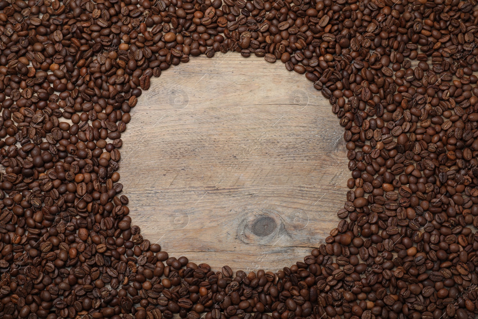 Photo of Frame roasted coffee beans on wooden table, flat lay. Space for text