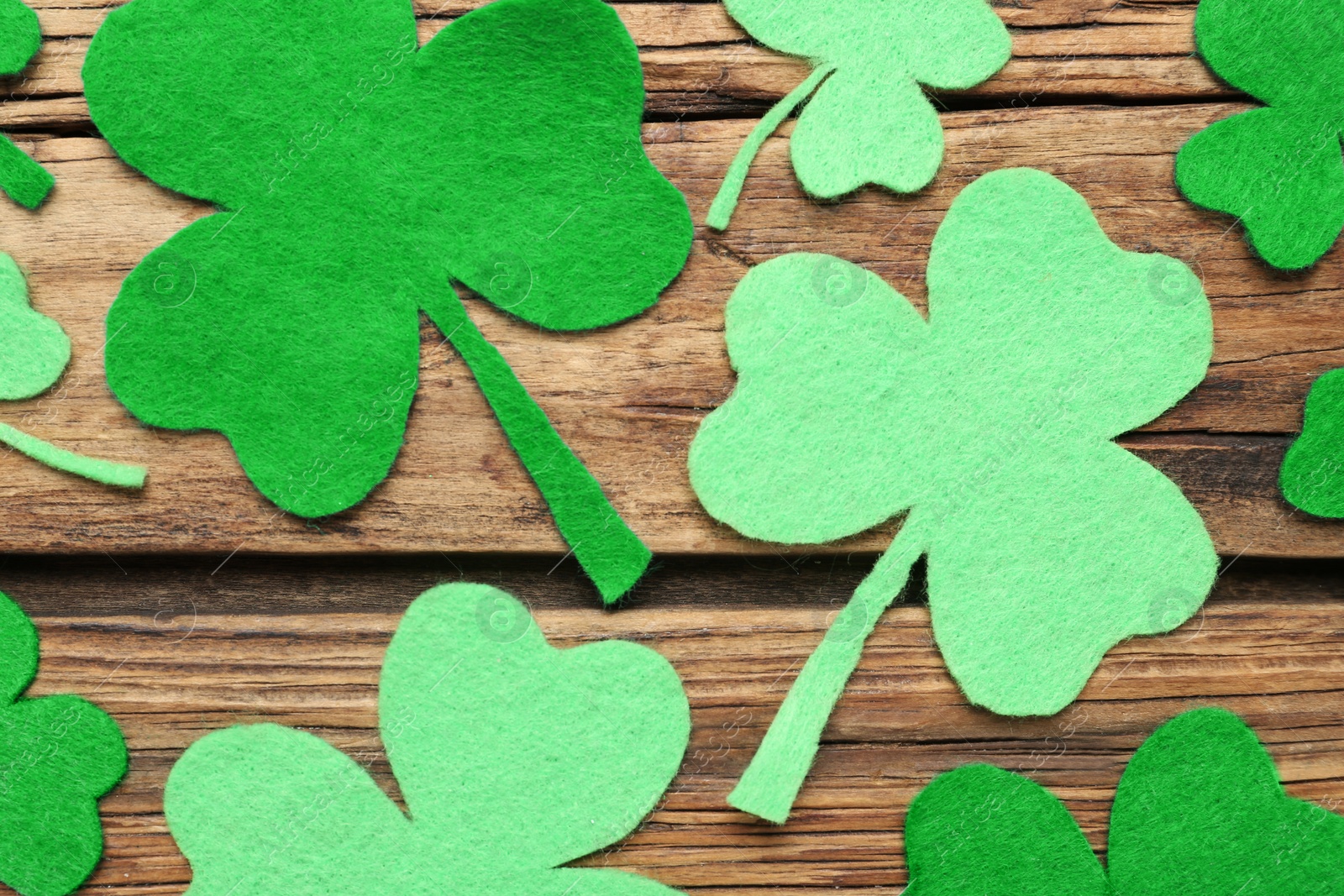 Photo of Decorative clover leaves on wooden background, flat lay. St. Patrick's Day celebration