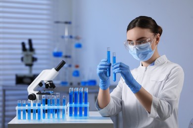 Photo of Scientist holding test tubes with samples in laboratory