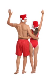 Lovely couple with Santa hats together on white background, back view. Christmas vacation