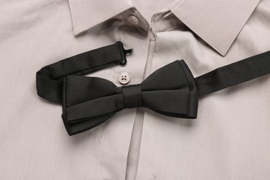 Photo of Stylish black bow tie on beige shirt, closeup
