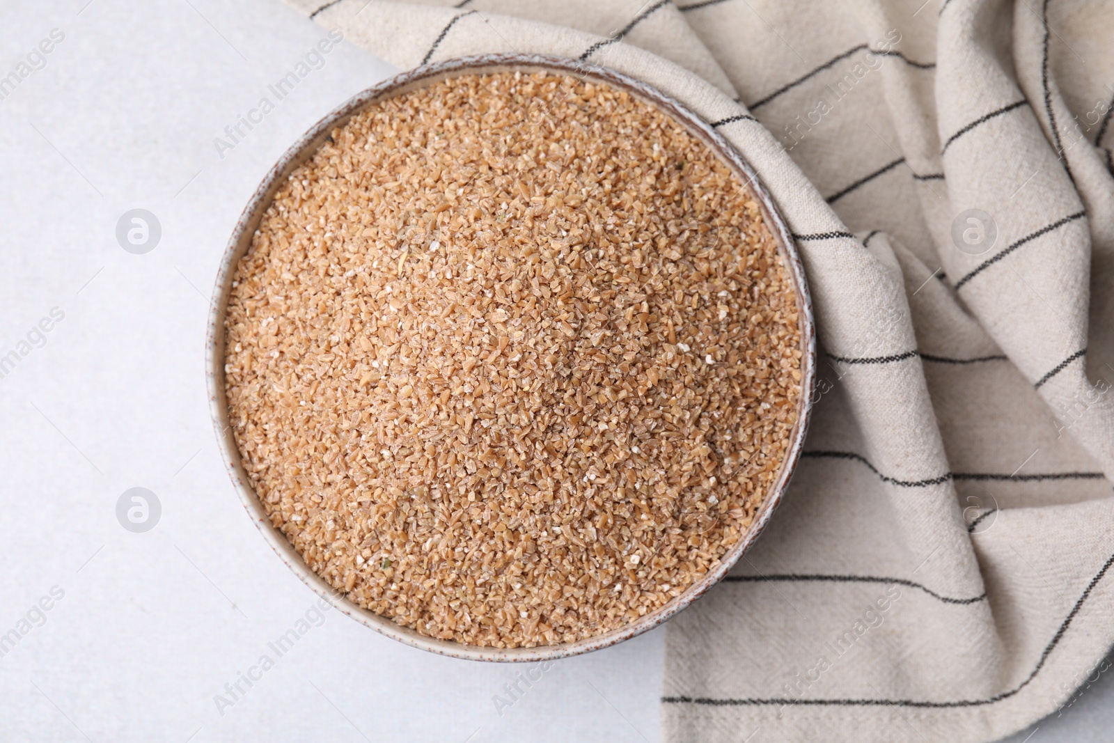 Photo of Dry wheat groats in bowl on light table, top view