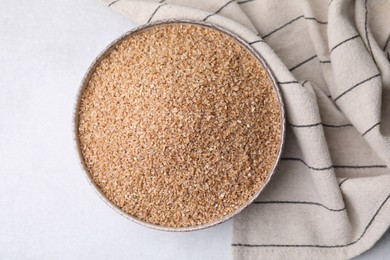 Dry wheat groats in bowl on light table, top view