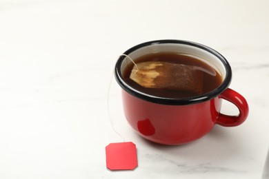 Tea bag in cup on white table, closeup. Space for text