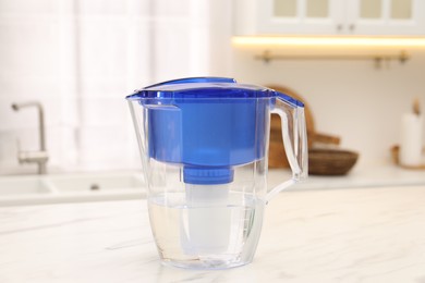 Photo of Water filter jug on white marble table in kitchen