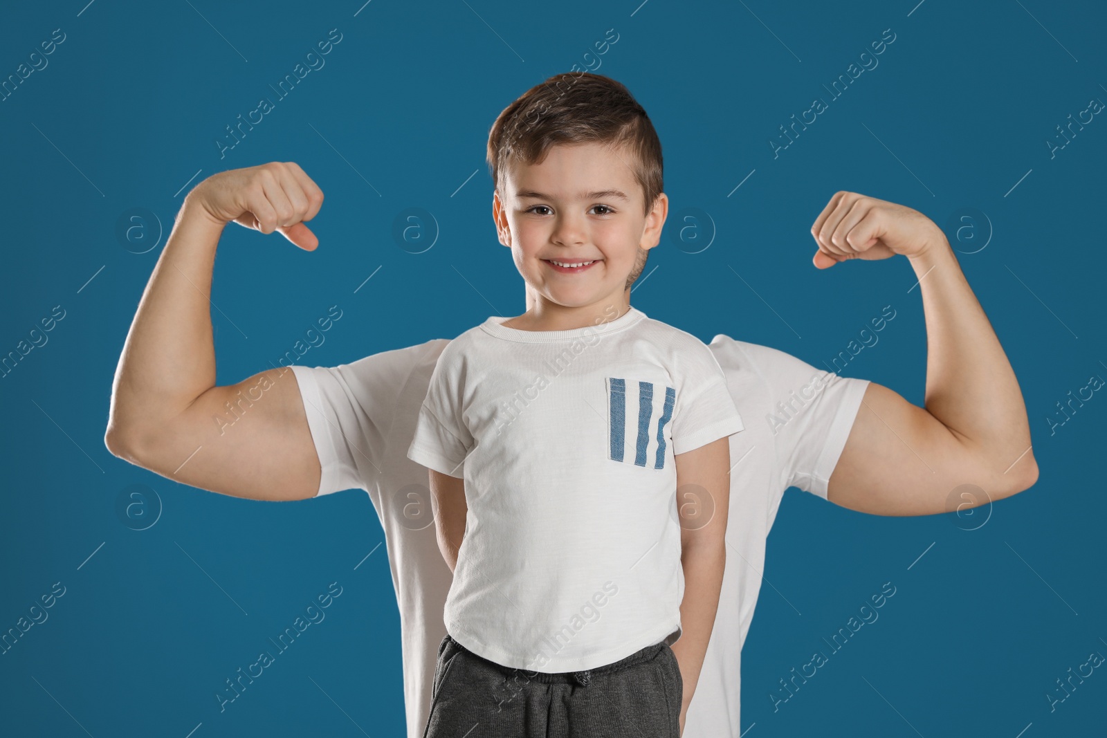 Photo of Portrait of sporty dad and his son on color background