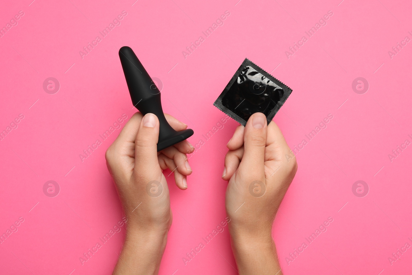 Photo of Woman with anal plug and condom on pink background, top view. Sex game