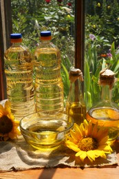 Organic sunflower oil and flowers on window sill indoors