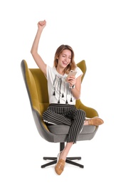 Young woman with smartphone sitting in armchair on white background