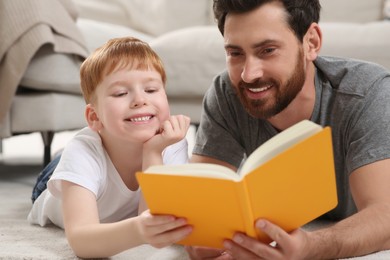 Photo of Father reading book with his child on floor at home, closeup