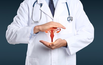 Image of Doctor demonstrating virtual icon with illustration of female reproductive system on dark background, closeup. Gynecological care 
