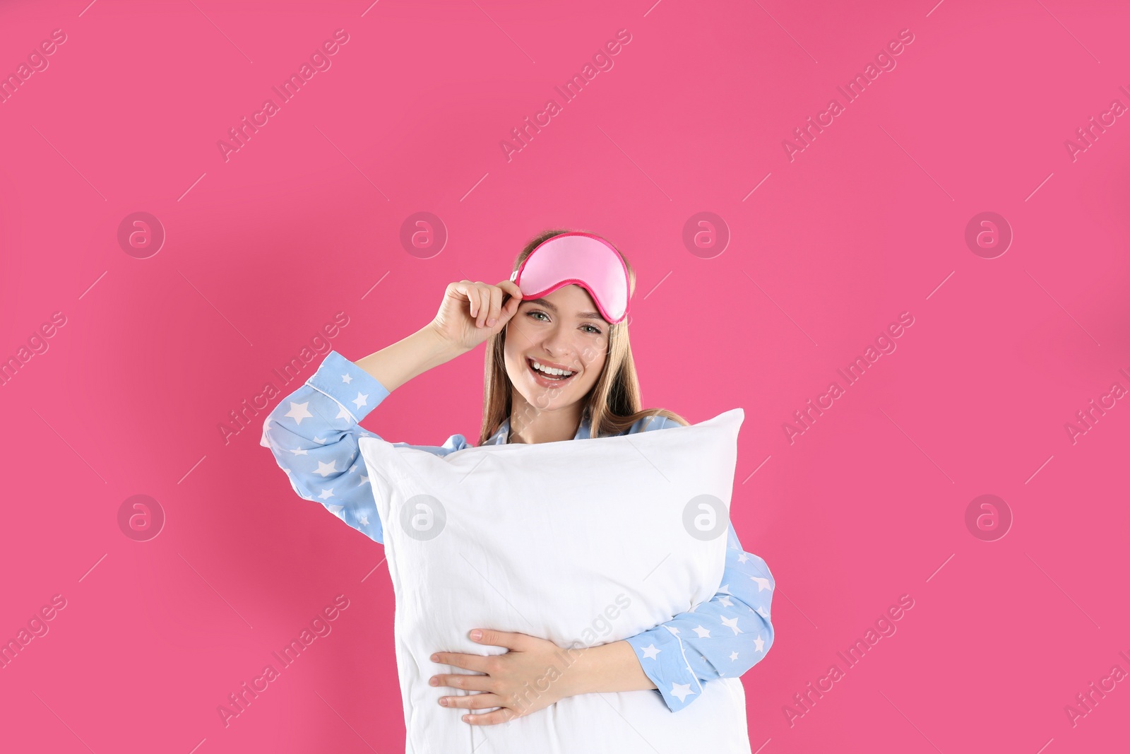 Photo of Young woman with pillow and sleep mask on pink background