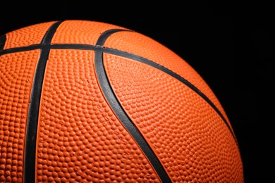 Photo of Orange basketball ball on black background, closeup