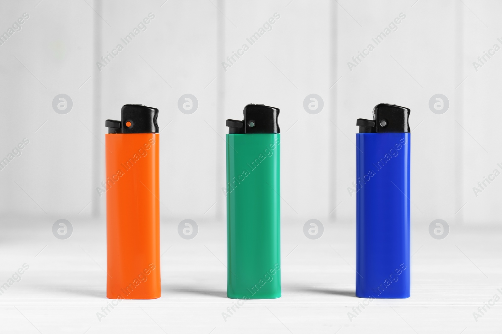 Photo of Stylish small pocket lighters on white wooden table