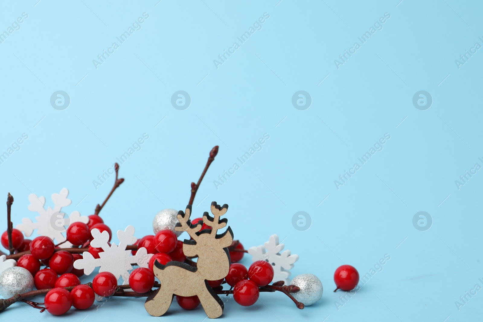 Photo of Wooden deer and decorative branches on light blue background. Winter season