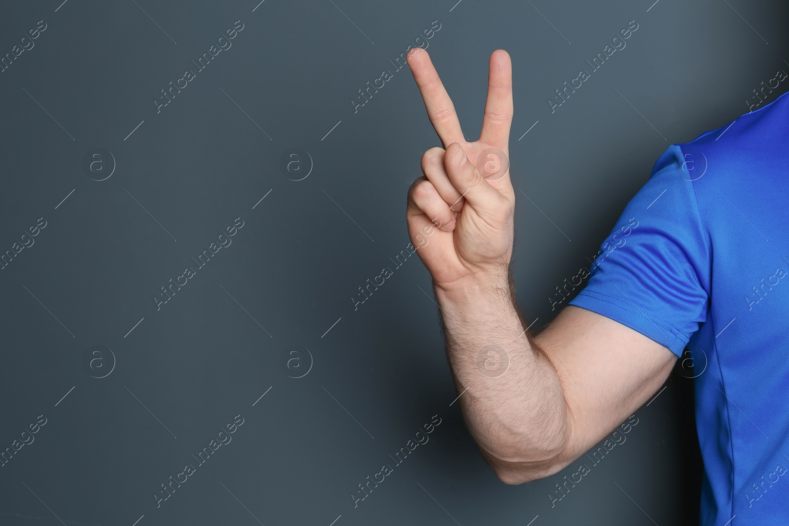 Photo of Young man showing victory gesture on color background. Space for text