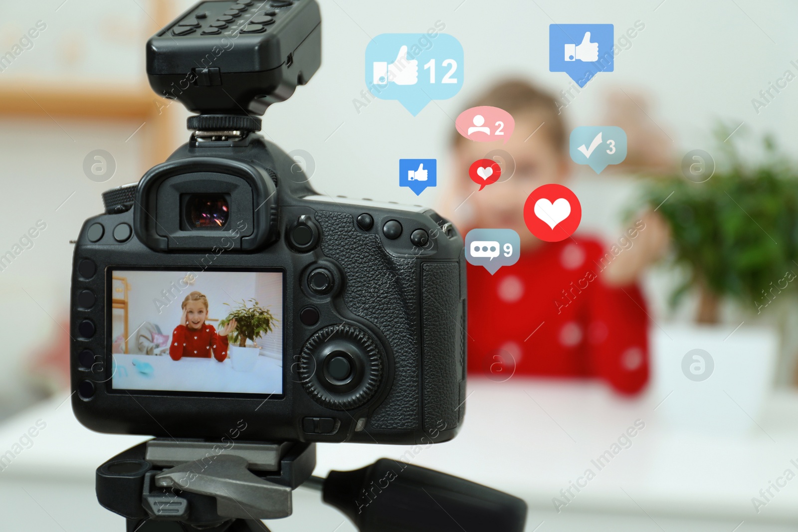 Image of Cute little blogger recording video at home, focus on camera