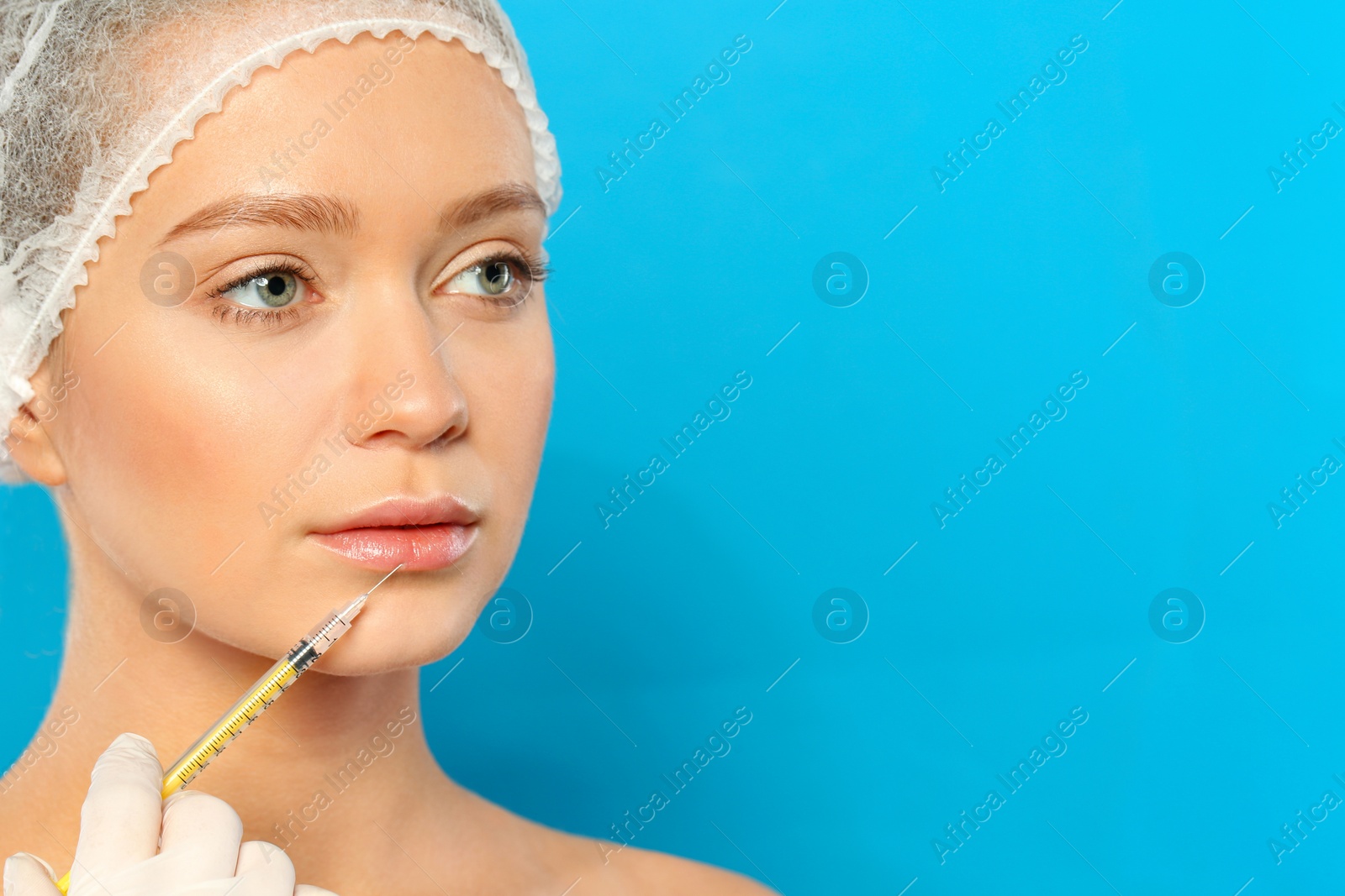 Photo of Young woman getting lips injection on color background, space for text. Cosmetic surgery
