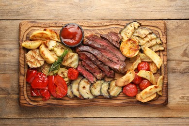 Photo of Delicious grilled beef steak with vegetables, rosemary and tomato sauce on wooden table, top view