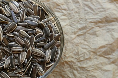 Photo of Bowl with sunflower seeds on parchment, top view. Space for text