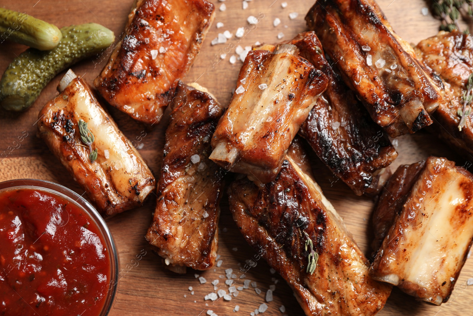 Photo of Delicious grilled ribs with sauce on wooden table, flat lay