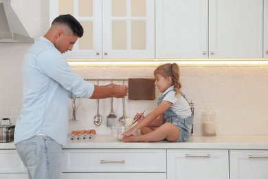 Little girl with her father cooking together in modern kitchen