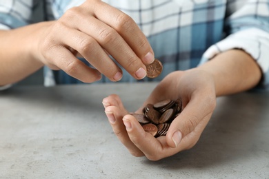 Photo of Young woman with coins at grey stone table, closeup